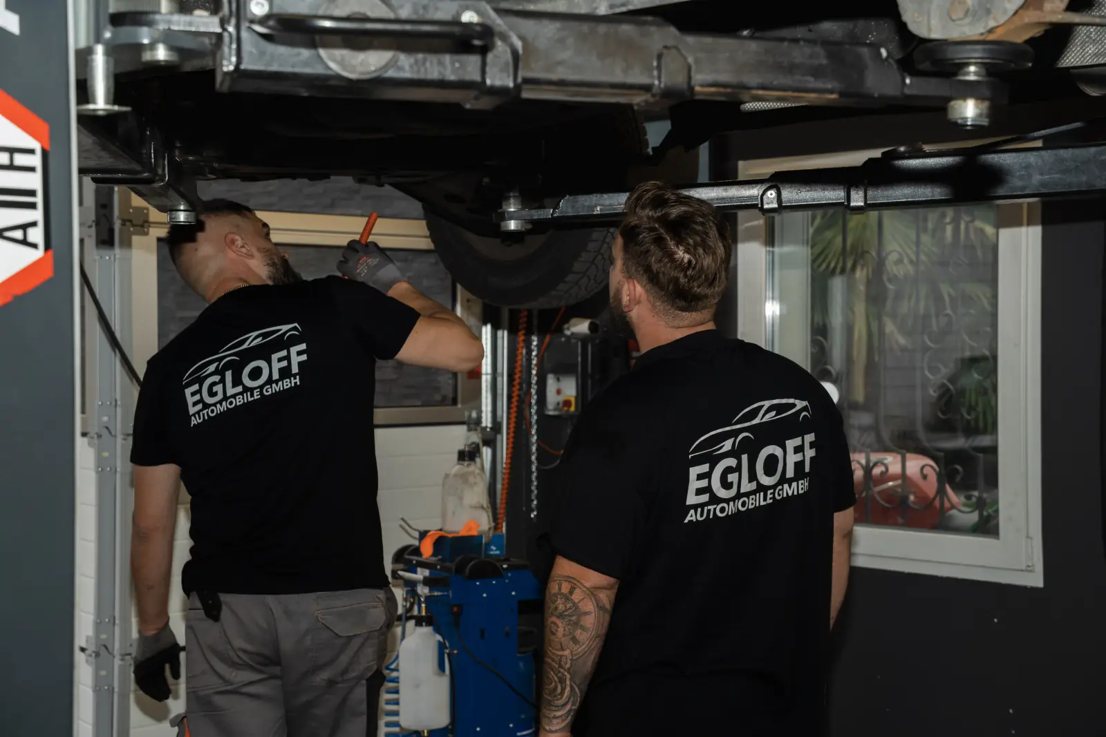 Zwei Mechaniker von Egloff Automobile beim Service unter einem Auto auf der Hebebühne